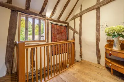 a wooden staircase in a room with a window at Extraordinary 15th Century timber framed cottage in famous Medieval village - The Tryst in Lavenham