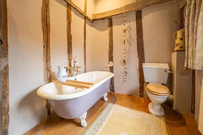 a bathroom with a white tub and a toilet at Extraordinary 15th Century timber framed cottage in famous Medieval village - The Tryst in Lavenham