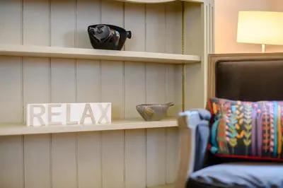 a room with a shelf with a relax sign and a chair at 2 Bed in Snape oc-wico in Snape