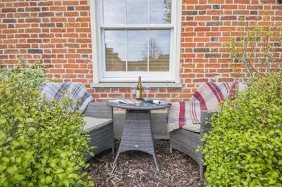 a patio with two chairs and a table and a window at 2 Bed in Blythburgh oc-wag2 in Blythburgh