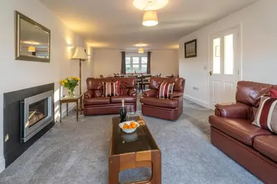 a living room with leather furniture and a fireplace at 4 The Birches - Aldeburgh Coastal Cottages in Aldeburgh