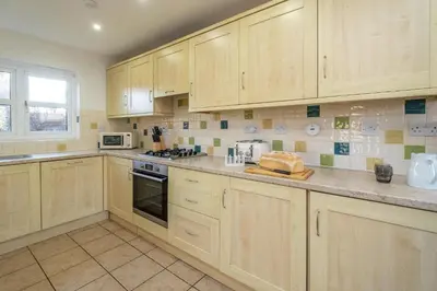 a large kitchen with wooden cabinets and appliances at 4 The Birches - Aldeburgh Coastal Cottages in Aldeburgh