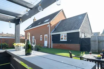 a table with a bottle of wine on a patio at 4 The Birches - Aldeburgh Coastal Cottages in Aldeburgh