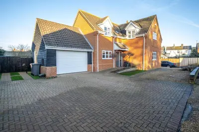 a house with a white garage on a brick driveway at 4 The Birches - Aldeburgh Coastal Cottages in Aldeburgh