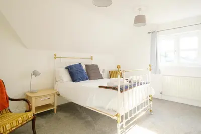 a bedroom with a white bed and a chair at 4 The Birches - Aldeburgh Coastal Cottages in Aldeburgh
