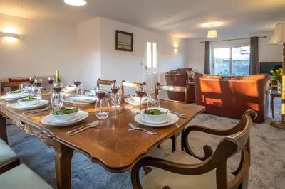 a wooden table with plates and wine glasses on it at 4 The Birches - Aldeburgh Coastal Cottages in Aldeburgh
