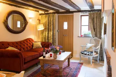 a living room with a couch and a table at Meddlars a historic cottage on the countryside edge of a vibrant Market Town in Hadleigh