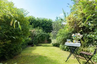 a garden with a table with flowers on it at Spadgers, a flax workers cottage next to fields in a Medieval Village in Long Melford
