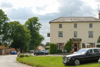 a black car parked in front of a white building at Spadgers, a flax workers cottage next to fields in a Medieval Village in Long Melford