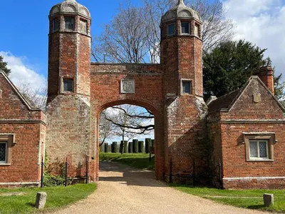 an entrance to an old brick building with an archway at Spadgers, a flax workers cottage next to fields in a Medieval Village in Long Melford