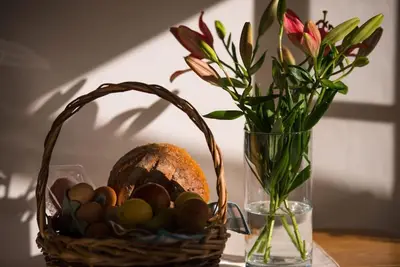 a basket of eggs and a vase with flowers on a table at Romney, a cosy Victorian cottage in a picturesque Suffolk village in Cavendish