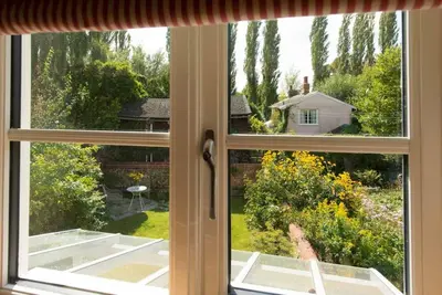an open window with a view of a garden at Romney, a cosy Victorian cottage in a picturesque Suffolk village in Cavendish