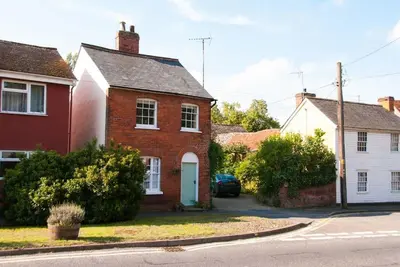 a red brick house with a white door on a street at Romney, a cosy Victorian cottage in a picturesque Suffolk village in Cavendish