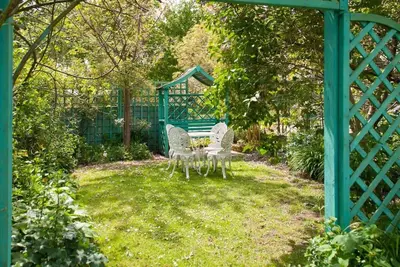 two chairs and a table in a yard with a fence at Queenies, an authentic Rural Style coastal cottage in a Nature Reserve in Farnham