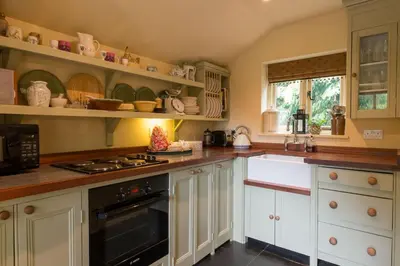 a kitchen with white cabinets and a stove top oven at Queenies, an authentic Rural Style coastal cottage in a Nature Reserve in Farnham