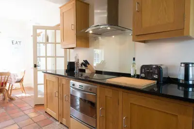 a kitchen with wooden cabinets and a stove top oven at The Old Steam Mill, luxury, spacious, beautiful grounds, stunning location in Hartest