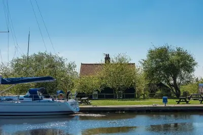 a boat is docked in the water next to a park at Navigation Cottage on the Historic Sea Lock overlooking the Nature Reserve in Maldon