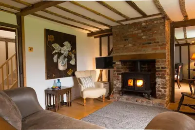 a living room with a fireplace and a couch and chair at Navigation Cottage on the Historic Sea Lock overlooking the Nature Reserve in Maldon