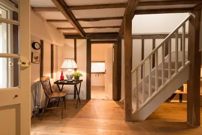 a hallway with a staircase and a table with a chair at Navigation Cottage on the Historic Sea Lock overlooking the Nature Reserve in Maldon