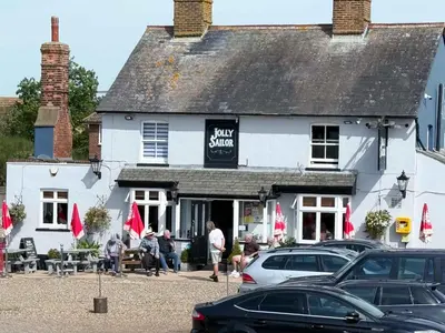 a white building with cars parked in front of it at Navigation Cottage on the Historic Sea Lock overlooking the Nature Reserve in Maldon