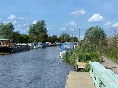 a boat is docked in a river next to a dock at Navigation Cottage on the Historic Sea Lock overlooking the Nature Reserve in Maldon