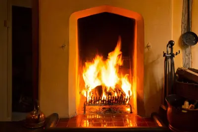 a fire in a fireplace with flames in it at The Old Monkey, a quirky bolthole on the edge of a historic Market Town in Hadleigh