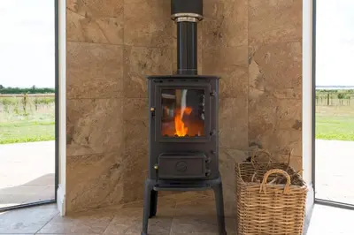 a wood stove in a stone wall with a basket at The Hexagon, wow what a location, views over the Essex marshes and sea in West Mersea