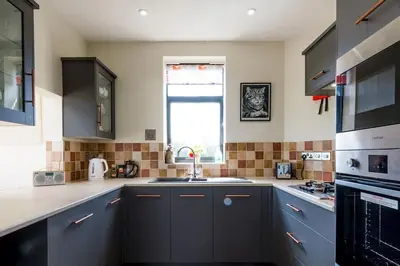 a kitchen with blue cabinets and a sink and a window at The Hexagon, wow what a location, views over the Essex marshes and sea in West Mersea