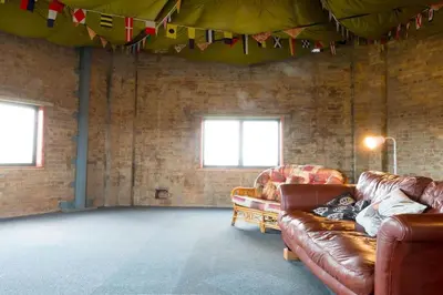 a living room with two leather couches and flags at The Hexagon, wow what a location, views over the Essex marshes and sea in West Mersea