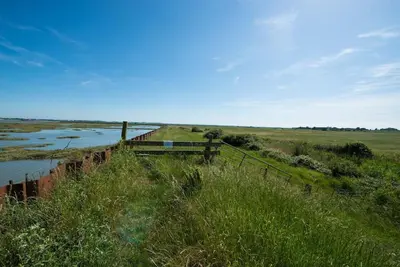 a bridge over a river next to a field at The Hexagon, wow what a location, views over the Essex marshes and sea in West Mersea