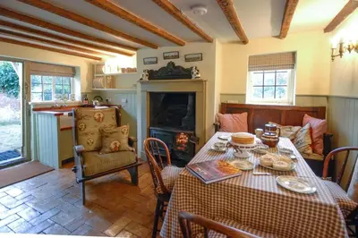 a dining room with a table and a fireplace at Laundry Cottage in a Nature Reserve - Sunday Times 100 coolest Cottages in Farnham
