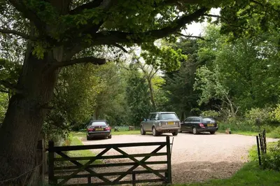 two cars parked on a dirt road under a tree at Laundry Cottage in a Nature Reserve - Sunday Times 100 coolest Cottages in Farnham