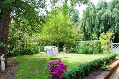 a garden with a table and some purple flowers at Laundry Cottage in a Nature Reserve - Sunday Times 100 coolest Cottages in Farnham