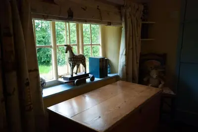 a window with a wooden horse statue sitting on a table at Cissys Cottage in a Nature Reserve, 7 minutes from Aldeburgh seafront in Farnham