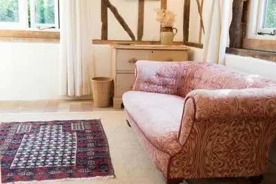 a living room with a couch and a rug at Bromans Barn a beautiful cottage by the Sea and Cudmore Nature Reserve in West Mersea
