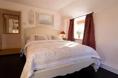 a bedroom with a white bed with a window at Farm Cottage a cute C17th cottage a walk across the fields to a great pub in Edwardstone