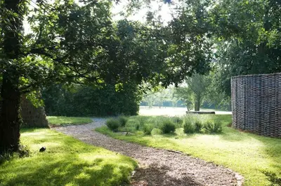 a gravel path in a park with a tree at Orchard Cottage cosy rustic comfort just across the fields to a great Pub in Edwardstone