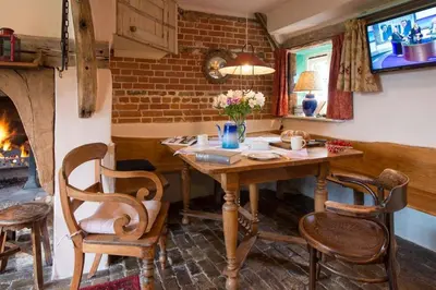 a dining room with a table and chairs and a fireplace at Orchard Cottage cosy rustic comfort just across the fields to a great Pub in Edwardstone