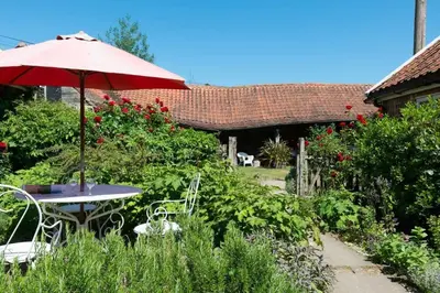a table and chairs with an umbrella in a garden at Rose Cottage rural cosiness with footpaths to the local Macro Brewery Pub in Edwardstone