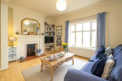 a living room with a blue couch and a fireplace at The Old Bakery - Aldeburgh Coastal Cottages in Aldeburgh