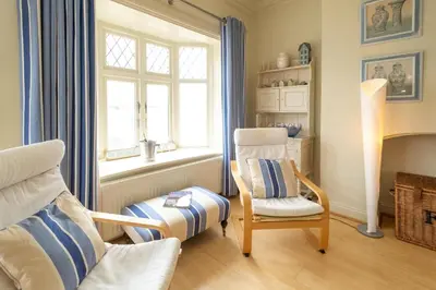 a living room with a chair and a window at The Old Bakery - Aldeburgh Coastal Cottages in Aldeburgh