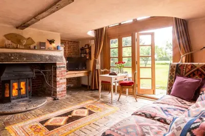 a living room with a couch and a fireplace at Dons Barn a Stunning cottage just a walk across the fields to a great pub in Edwardstone