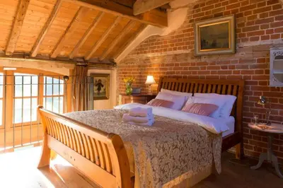 a bedroom with a large bed in a brick wall at Dons Barn a Stunning cottage just a walk across the fields to a great pub in Edwardstone