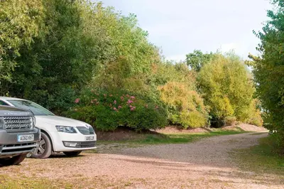 a white car parked on the side of a dirt road at Dons Barn a Stunning cottage just a walk across the fields to a great pub in Edwardstone