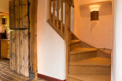 a staircase in a house with a wooden door at Dons Barn a Stunning cottage just a walk across the fields to a great pub in Edwardstone