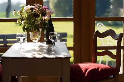 a table with two wine glasses and a vase of flowers at Dons Barn a Stunning cottage just a walk across the fields to a great pub in Edwardstone
