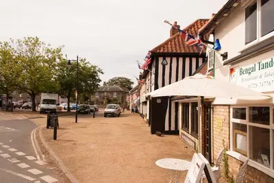 a street in a town with cars parked on the street at Wren Cottage, a very cosy historic Coastal Cottage in a pretty little village in Wickham Market