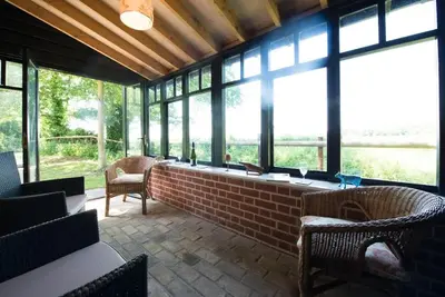 a large room with windows and chairs and tables at The Wobbin, Remote, Comfort, Sea Views and the beautiful Essex Marshes in West Mersea