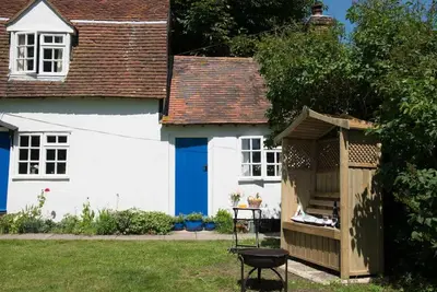 a white and blue house with a wooden shed at The Wobbin, Remote, Comfort, Sea Views and the beautiful Essex Marshes in West Mersea