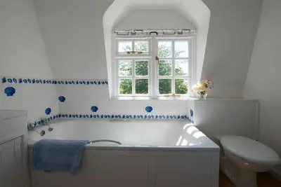 a bathroom with a tub and a toilet and a window at The Wobbin, Remote, Comfort, Sea Views and the beautiful Essex Marshes in West Mersea